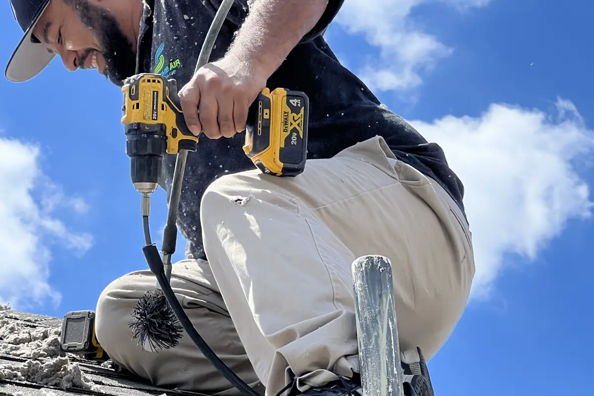 Air Central tech with drill cleaning dryer vent on rooftop