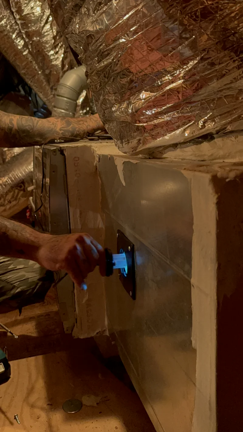 Air Central tech installing UV light inside HVAC coil box in Austin home